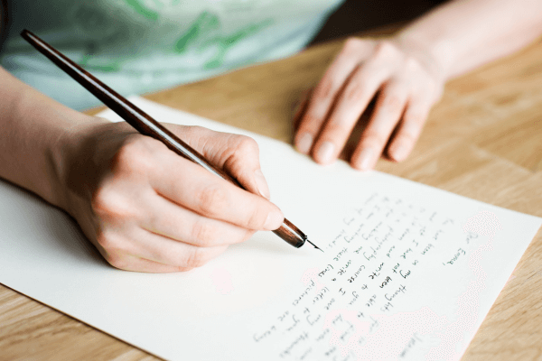 Une personne écrit une lettre au stylo plume