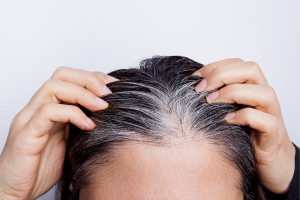 Une femme touche ses cheveux blancs
