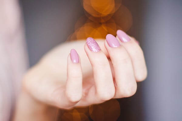 Ongles avec du vernis rose et vernis rose pailleté