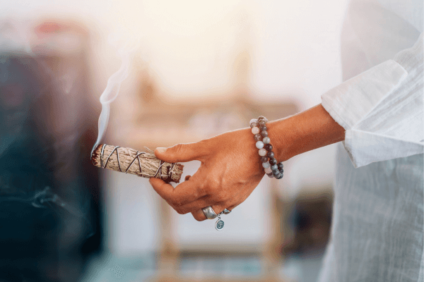 Une femme tient une sauge allumée dans la main