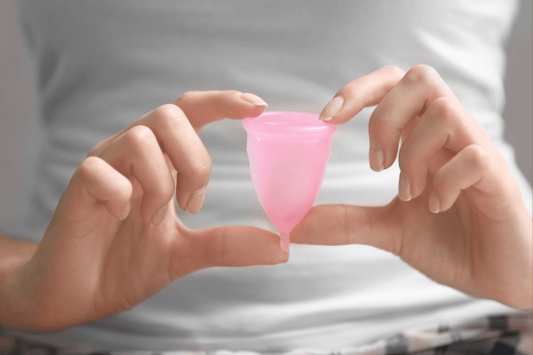 Une femme tient une coupe menstruelle entre ses doigts